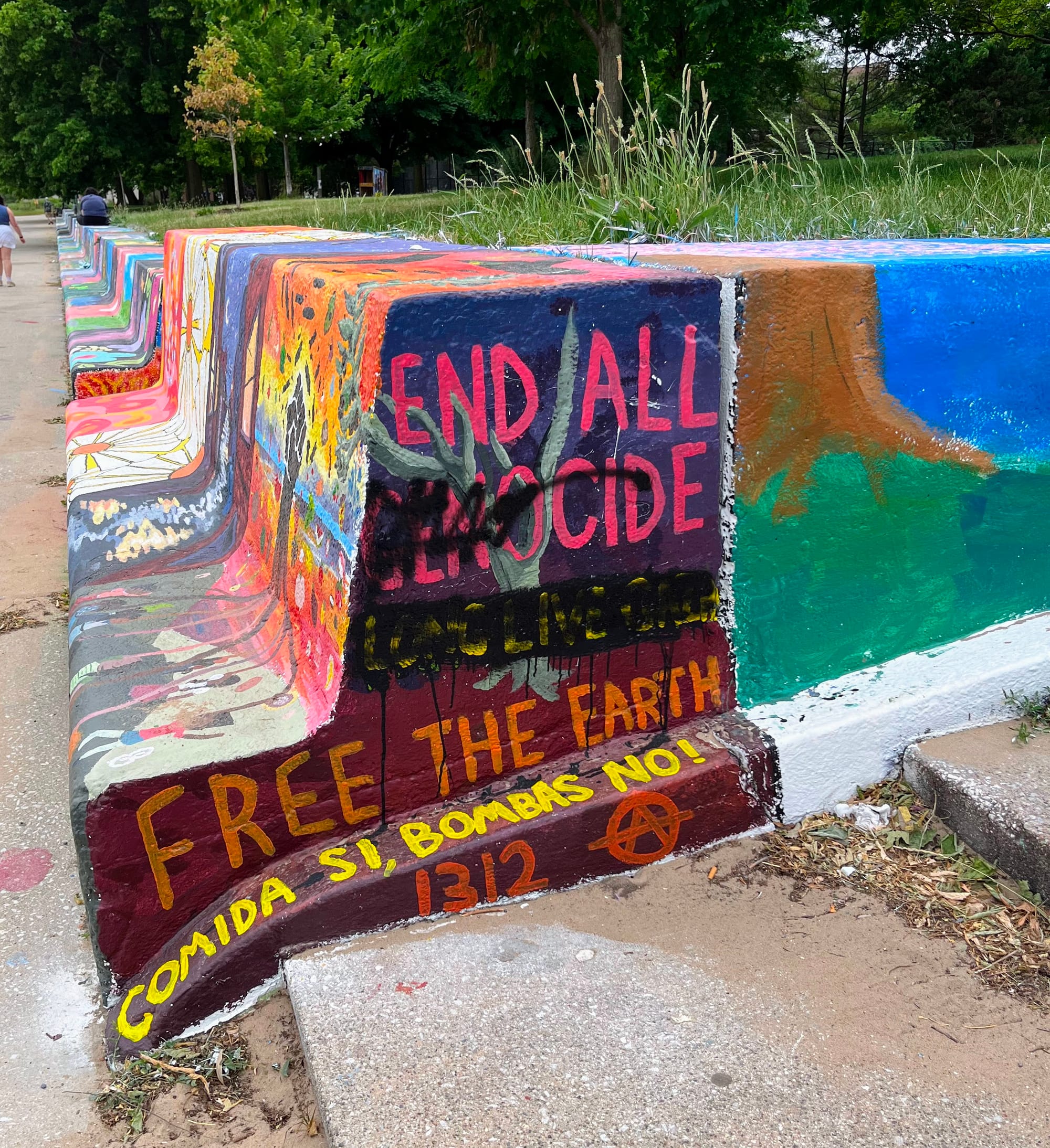 A mural that includes the words "end all genocide" is smeared with black paint.