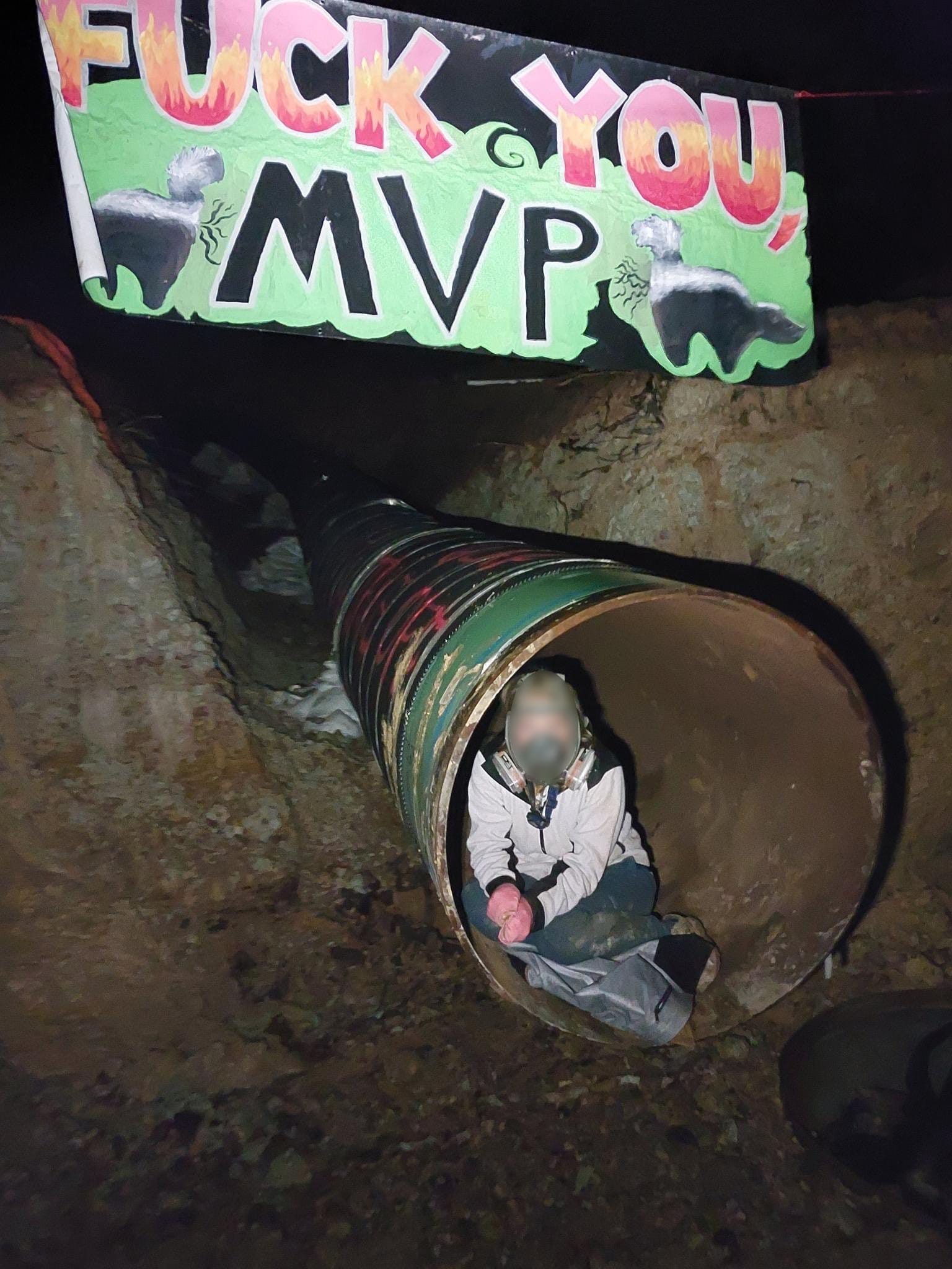 A protester in a gas mask is seen in the opening of a pipeline under construction.