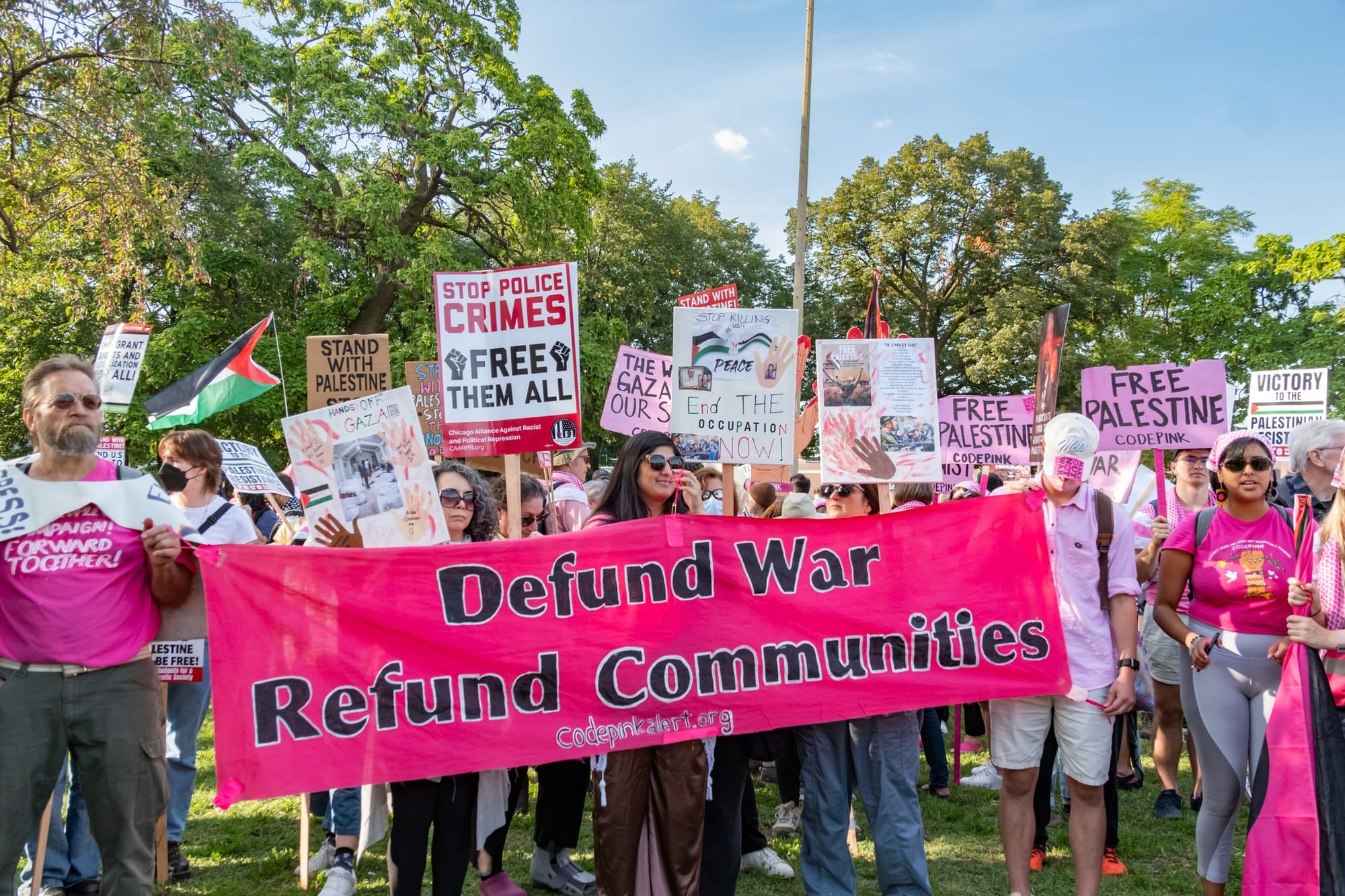 Protesters hold a banner that reads, "Defund War Refund Communities."