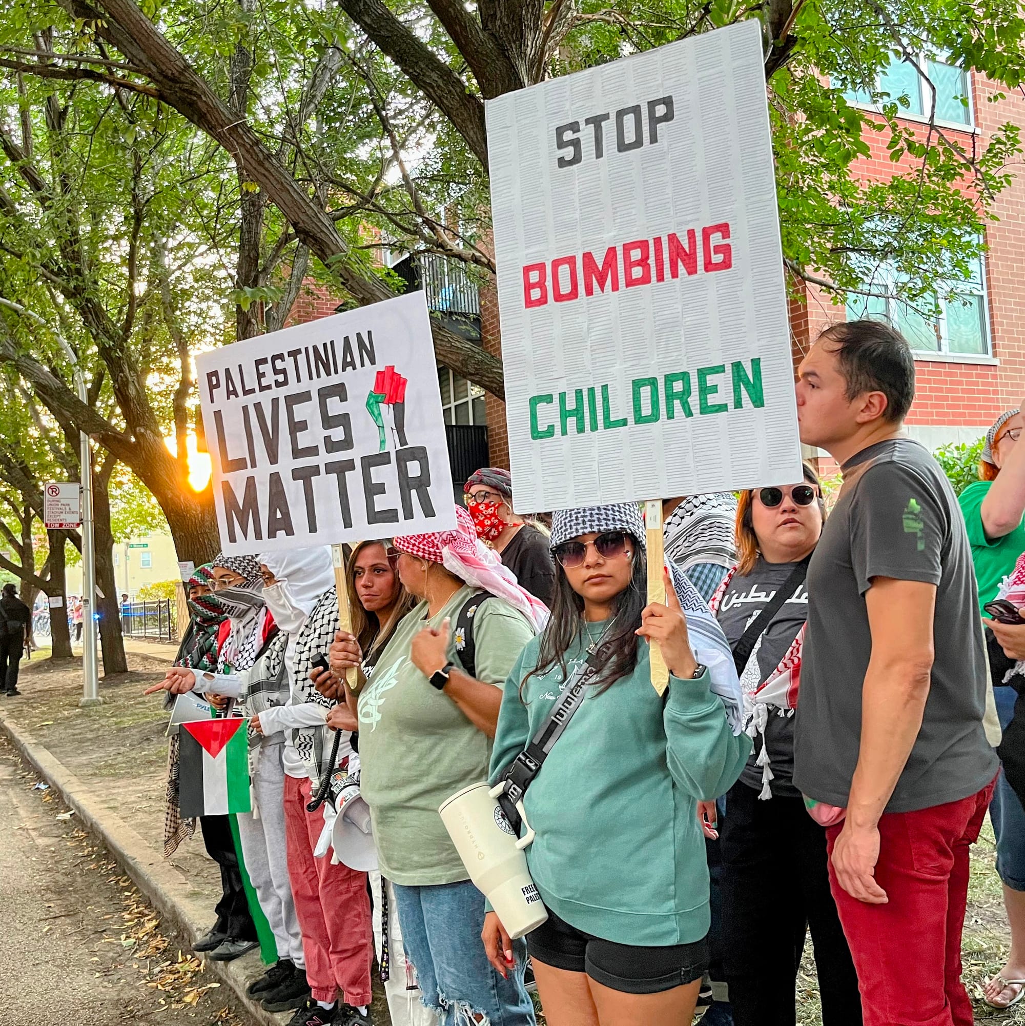 Protesters hold signs that with messages including "Stop Bombing Children."