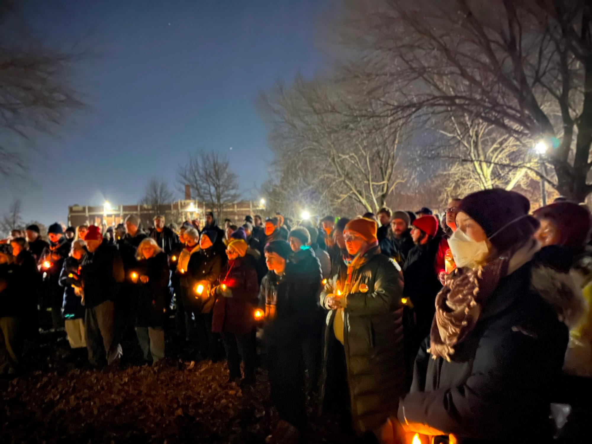 A blurred image of protesters at a vigil holding plastic candles.