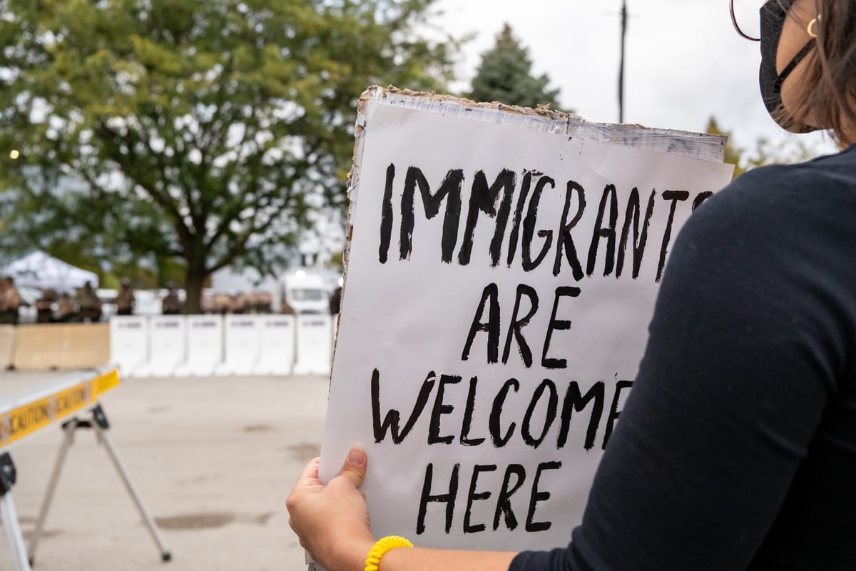 A protester holds a sign that says, "Immigrants are welcome here."