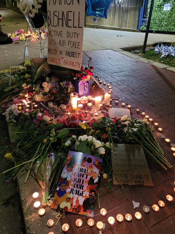 Flowers candles and signs assembled in tribute to Aaron Bushnell outside the Israeli Embassy.