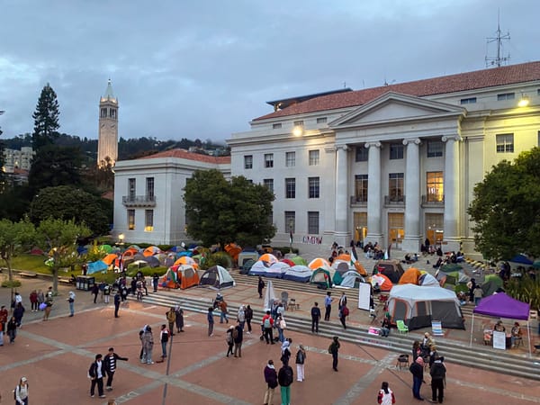 Tents line the steps of Sprout Hall at UC Berkeley. Protesters and students gather in the plaza outside the building.
