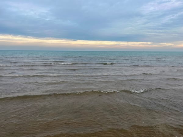 Waves roll gently onto a Lake Michigan beach in Chicago. The sky is overcast.