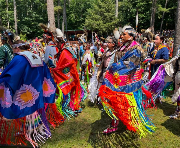 Women in traditional Native regalia dance at a powwow. 