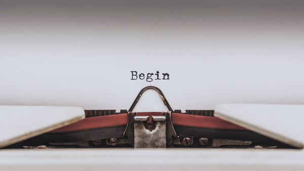 A piece of white paper in a typewriter. The word "begin" has been typed.